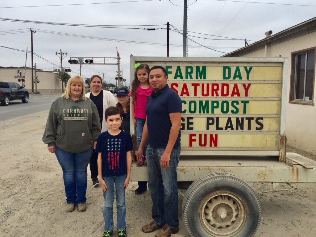 Crew and kids at sign by Farm Day